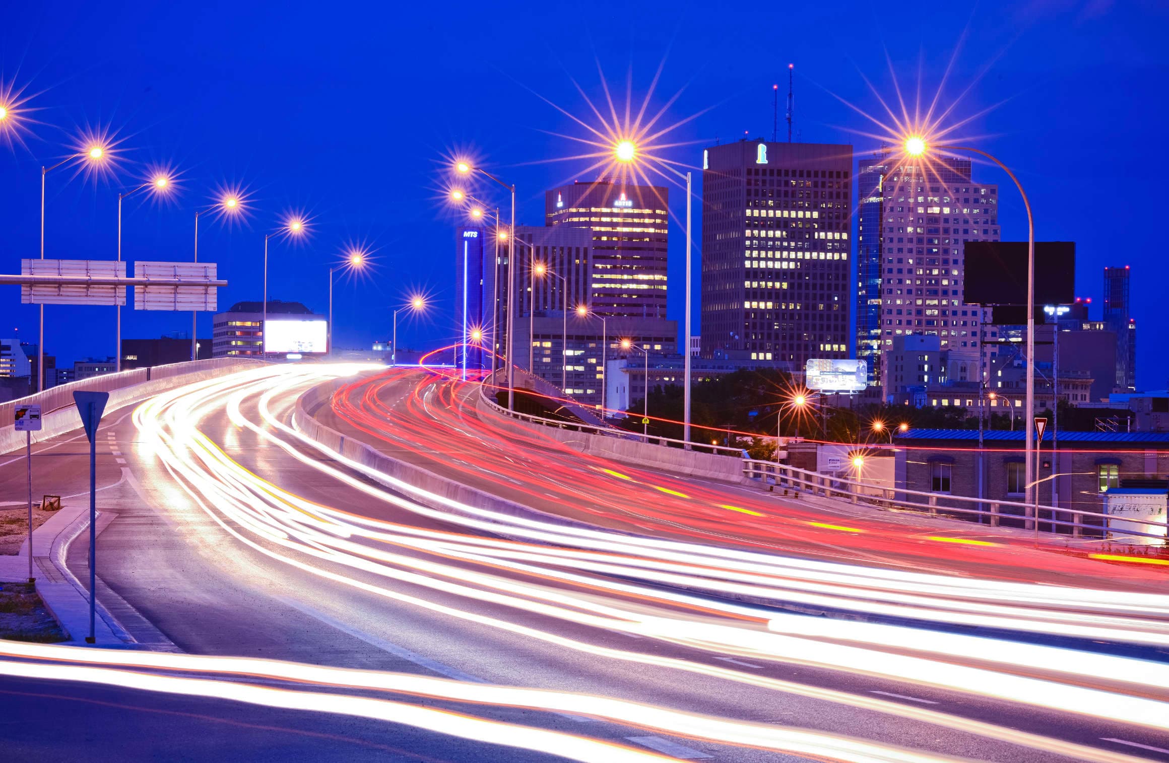 Night image of car lights driving over a bridge into a city