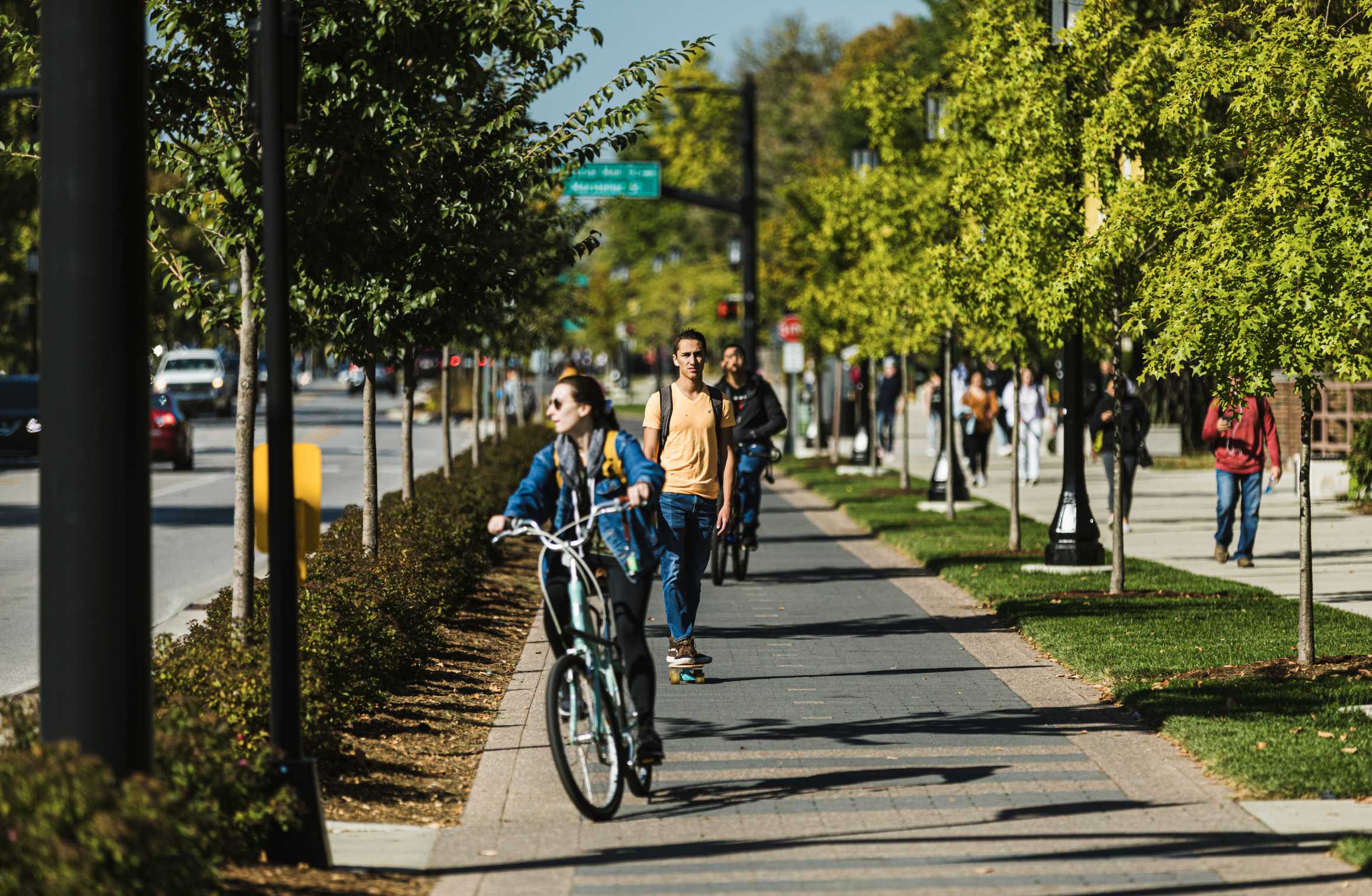 Cyclist, skateboarder and students on pedestrian walkway