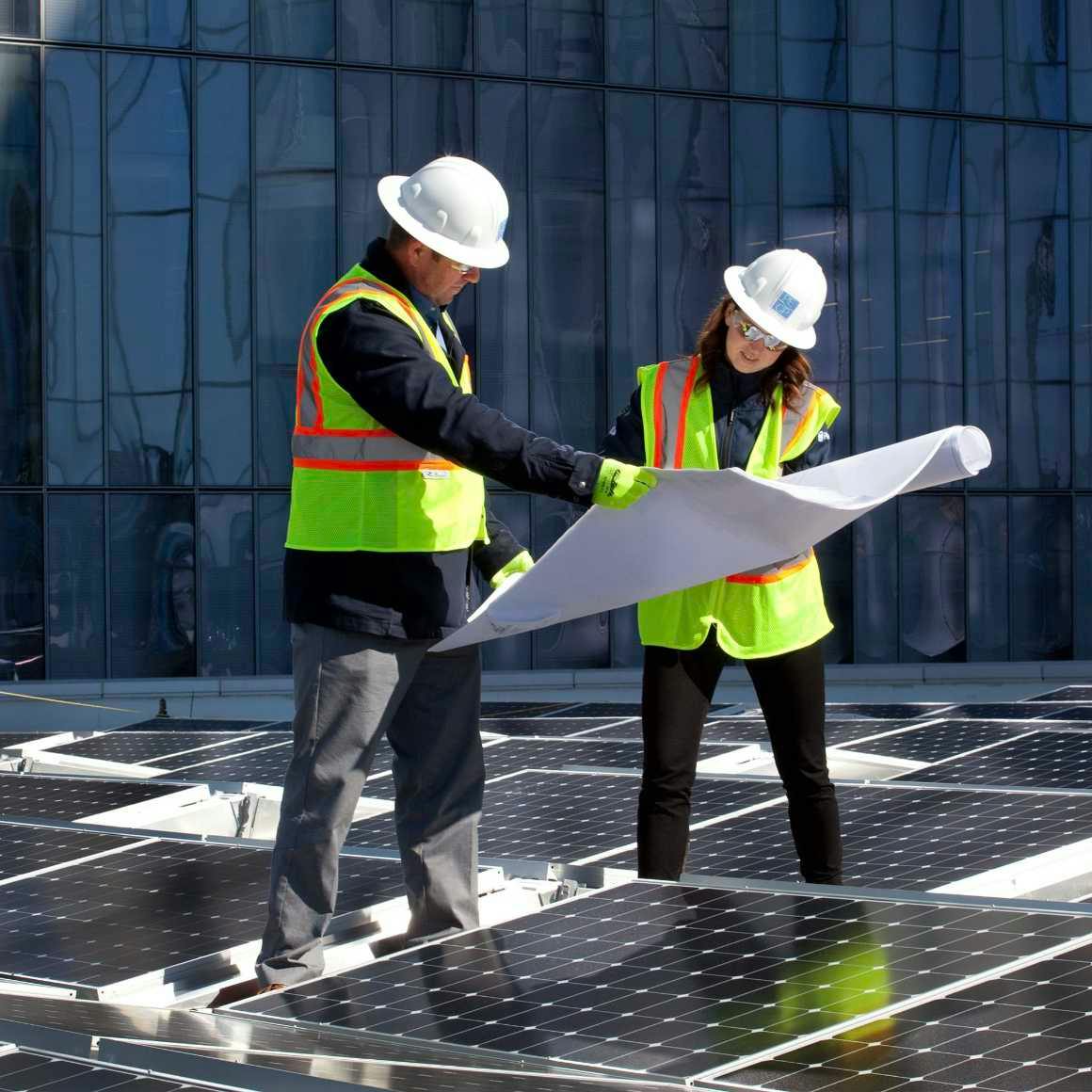 Infrastructure specialists standing among solar panels, reviewing plans at Long Beach Civic Center
